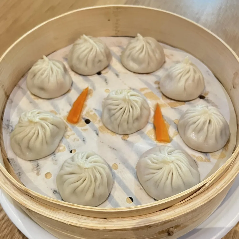 Delicate steamed soup dumplings served in a bamboo steamer at Dumpling King Asian Cuisine in Sacramento